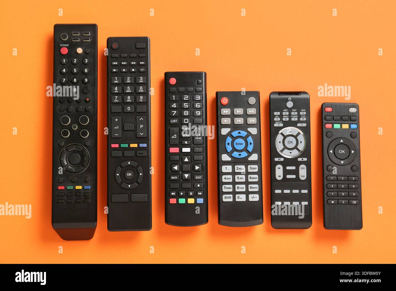 Different modern TV remote controls on orange background Stock Photo