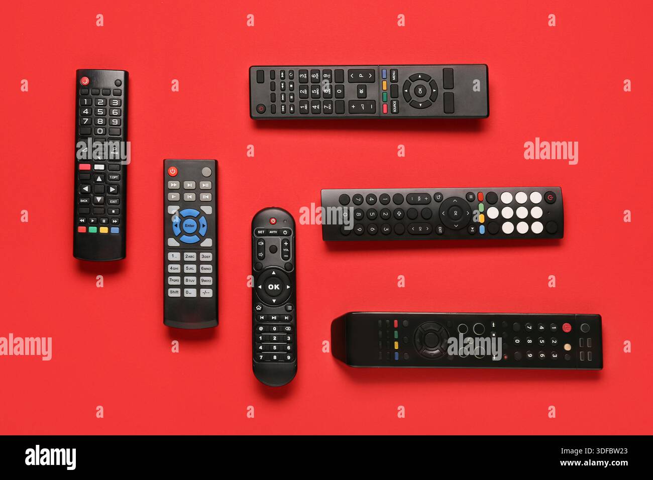 Different modern TV remote controls on red background Stock Photo