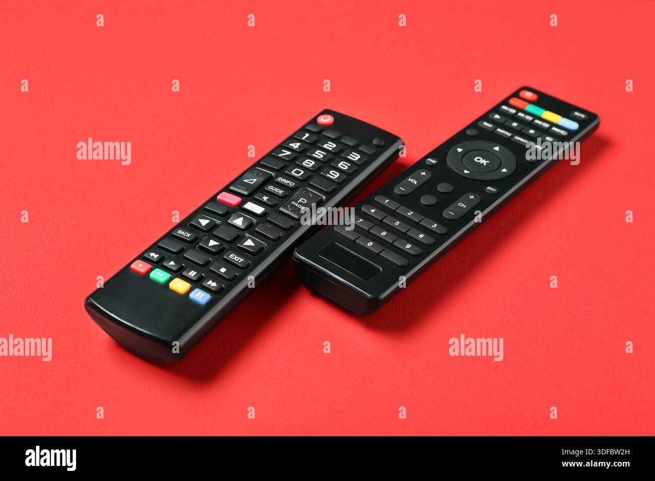 Modern TV remote controls on red background Stock Photo