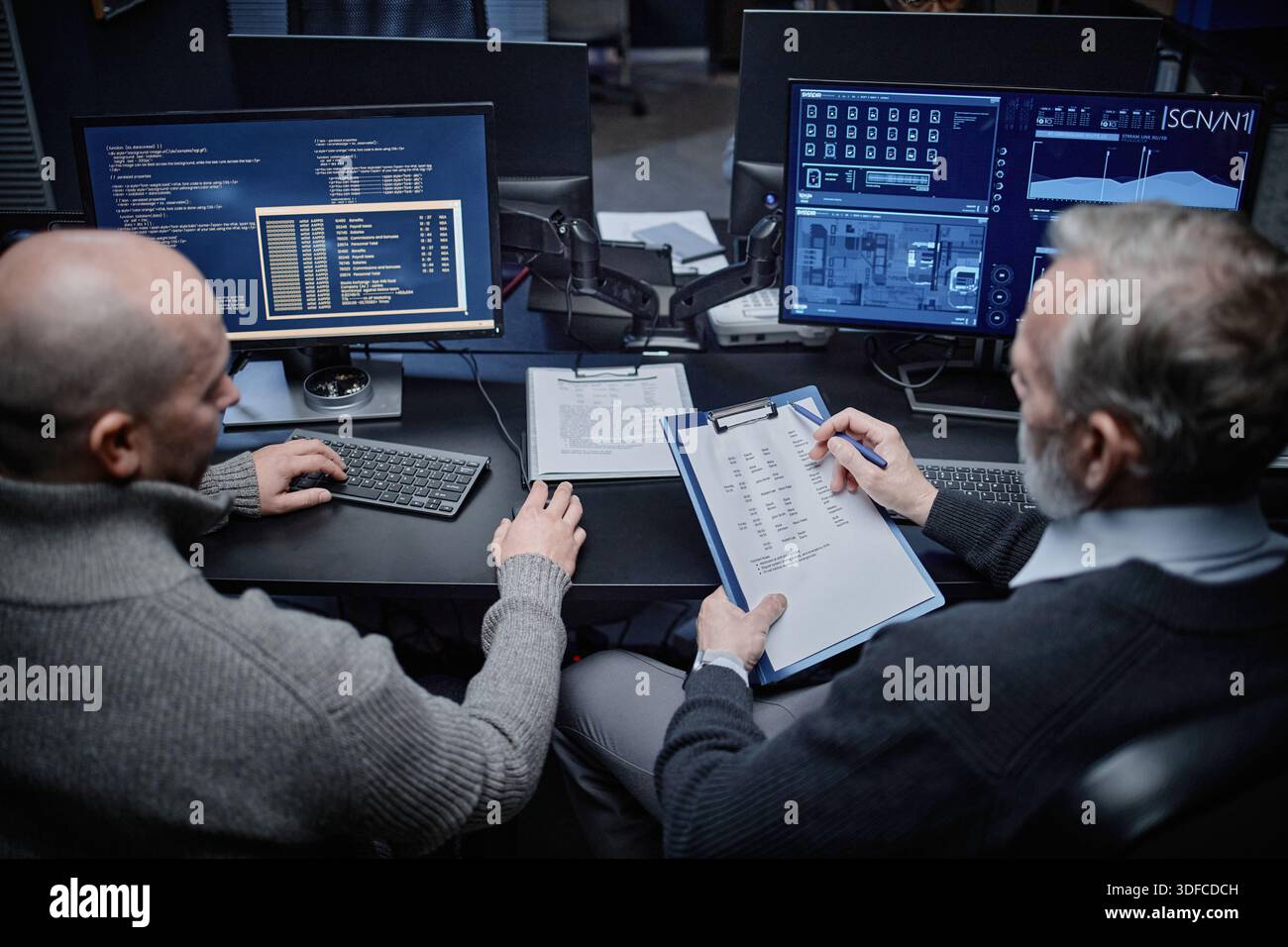 Middle Aged Caucasian Men Analyzing Cybersecurity Data on Computer Monitors Stock Photo