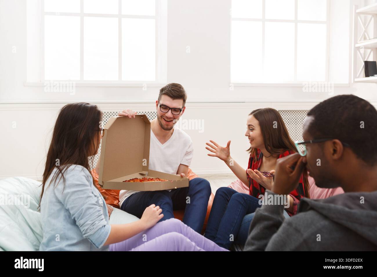 Students sharing pizza at home party Stock Photo