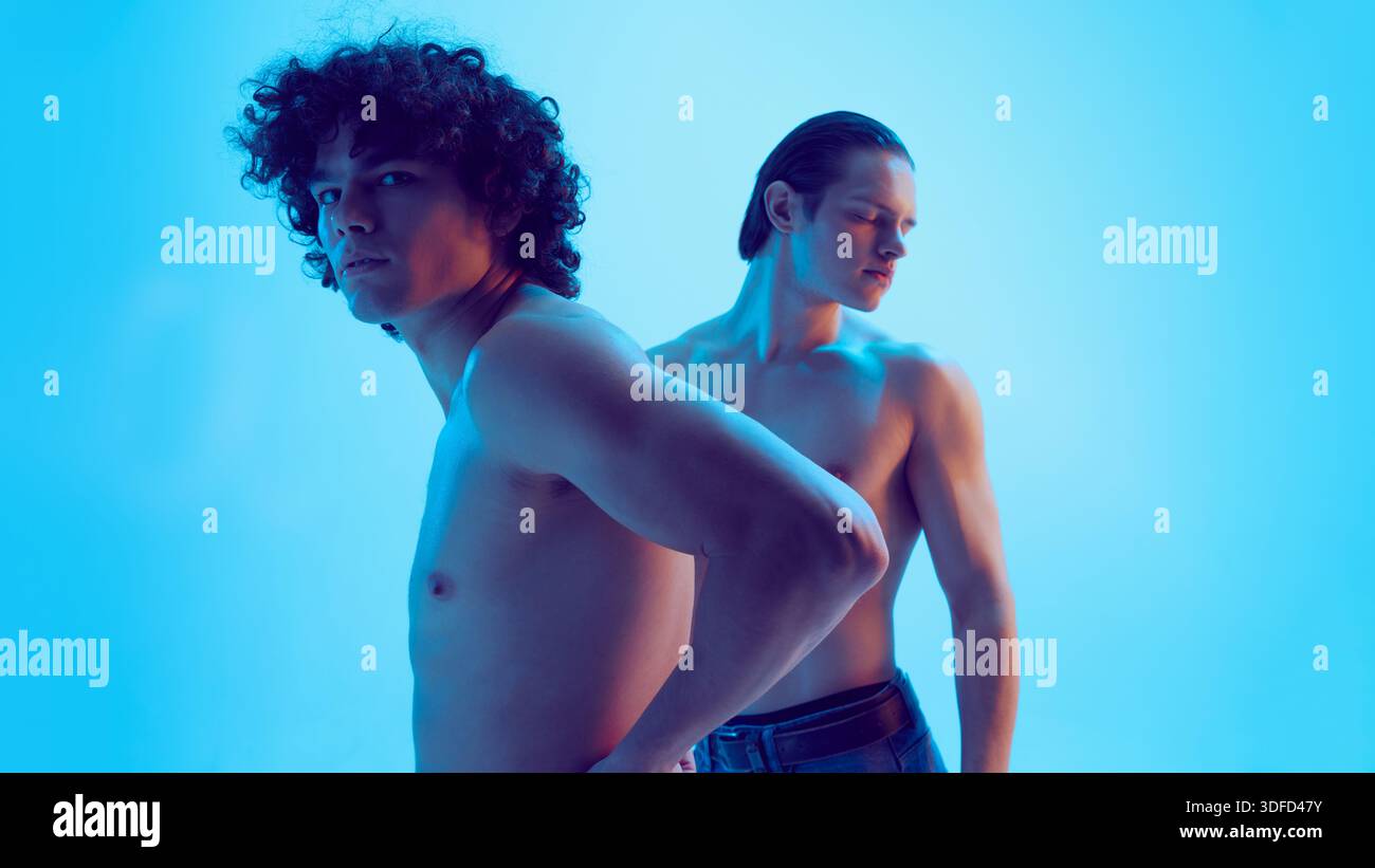 Two young men side view with alert posture in blue light. Stock Photo