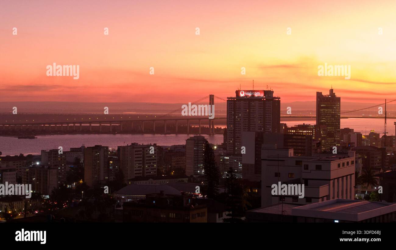 Aerial view of the cityscape bathed in the warm glow of sunset, with ...