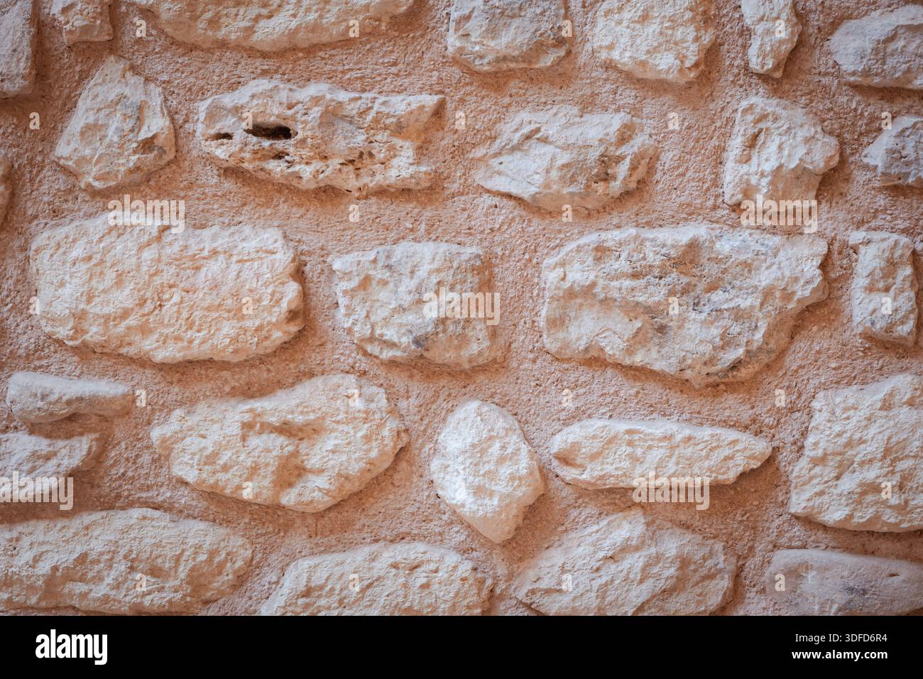 Rustic stone wall texture forming natural architectural background with rough beige and light brown rocks and aged mortar pattern Stock Photo