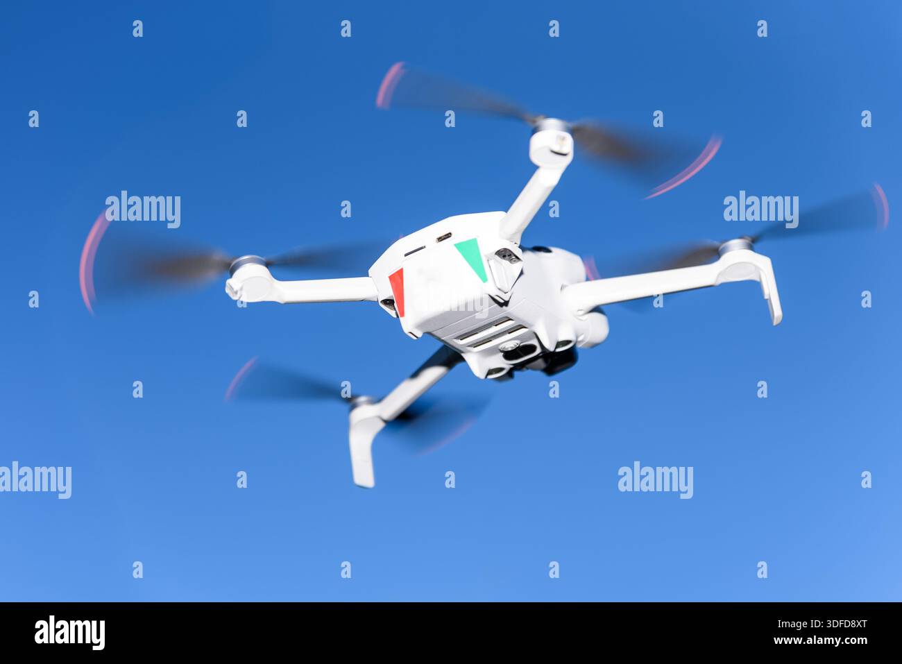Flying drone in clear blue sky, modern unmanned aerial vehicle in flight. Concept of aerial photography, technology, innovation, robotics, and future Stock Photo