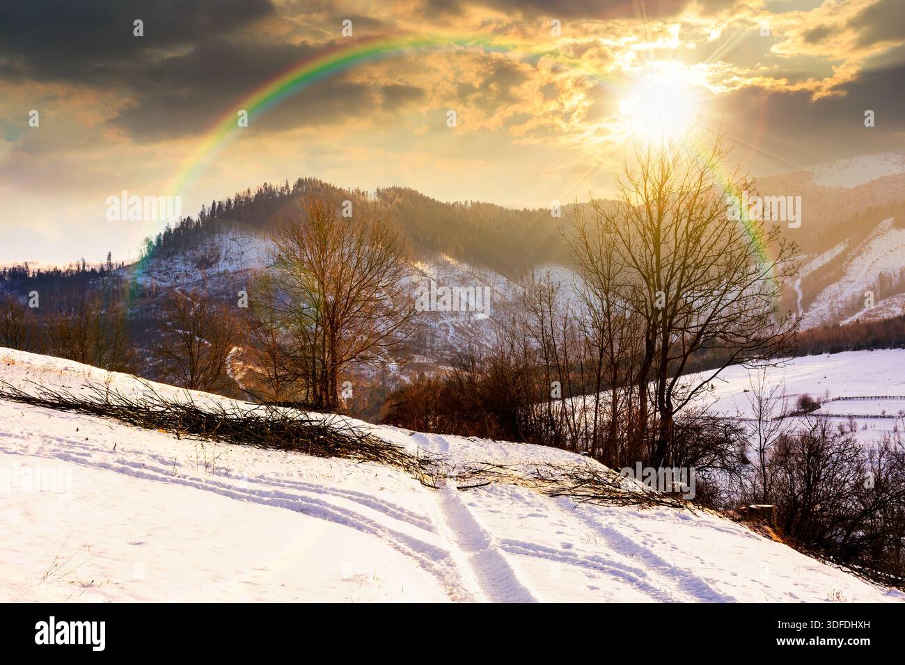 winter landscape with snow covered forested hills at sunset. mountains in cold weather in evening light. rural scene. christmas holiday in alpine regi Stock Photo