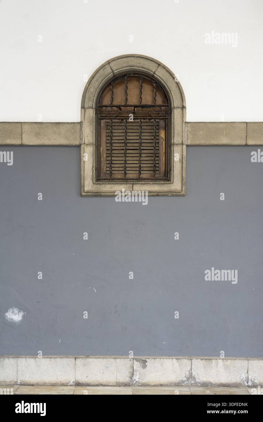Arched window with wooden shutter on two-toned wall Stock Photo