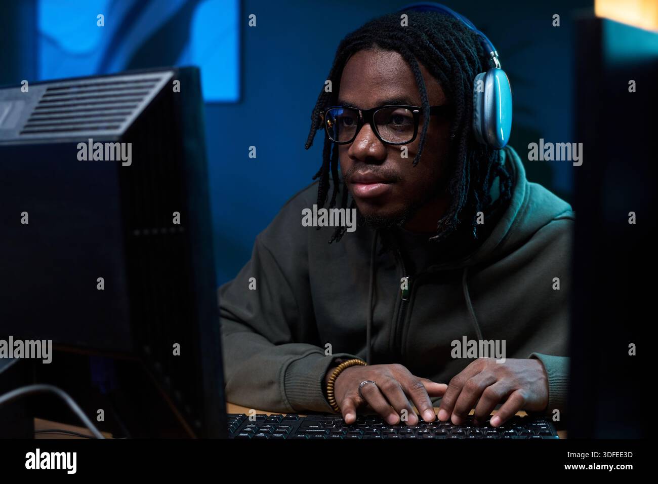 Young Black Man Wearing Headphones Using Computer While Concentrating Stock Photo