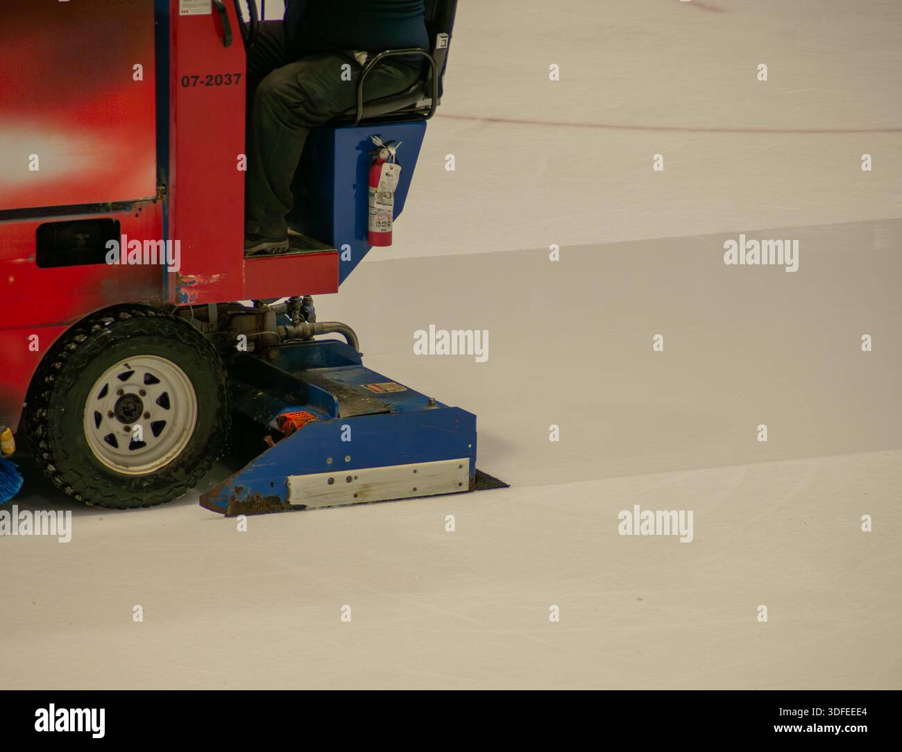 The Arena Zamboni ice surfacing machine scrapes the old ice and lays down a sheet of fresh water which will freeze quickly into a fresh sheet of ice f Stock Photo