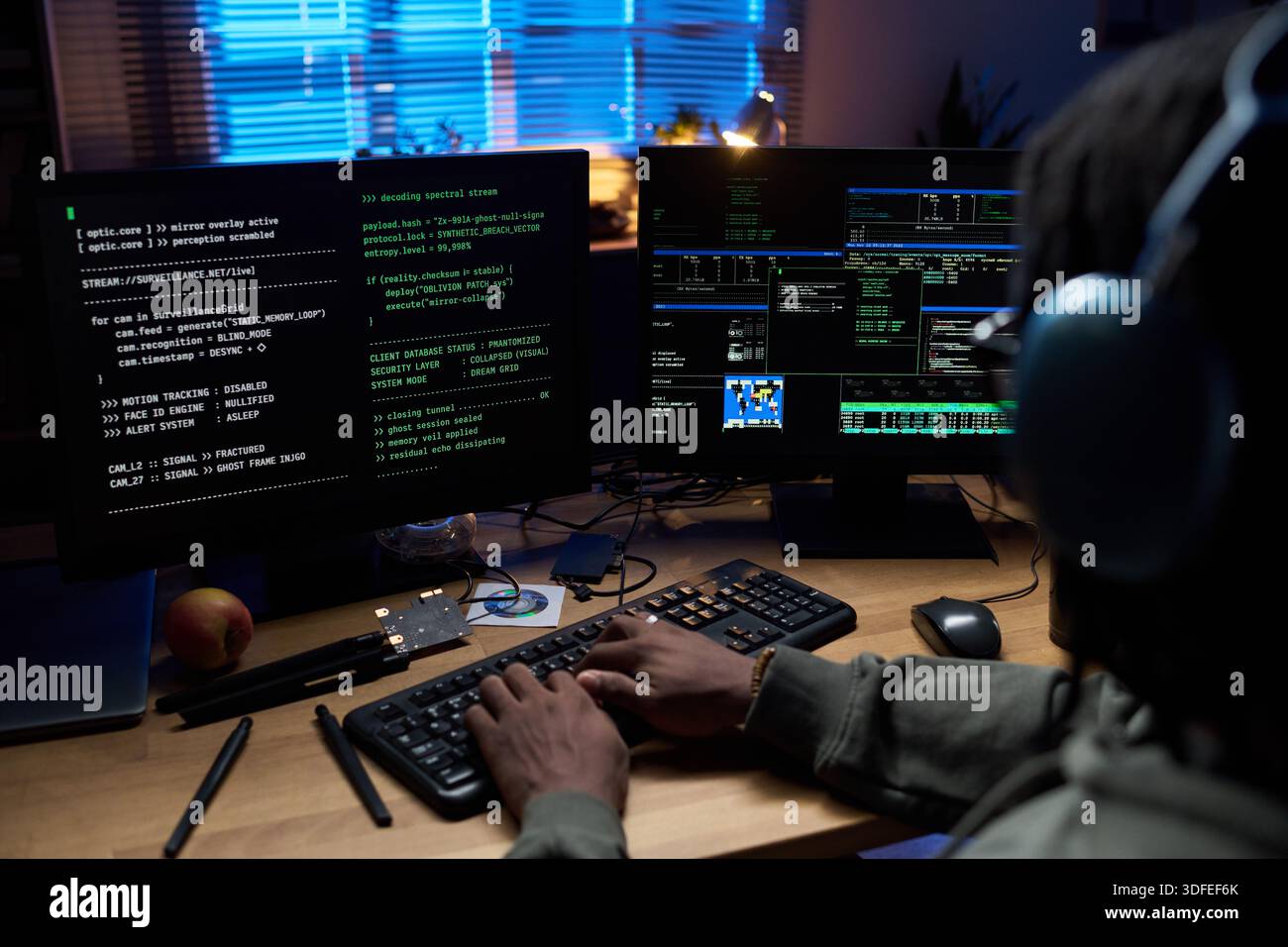 Young Black Man Coding Software on Computer Monitors at Night Stock Photo