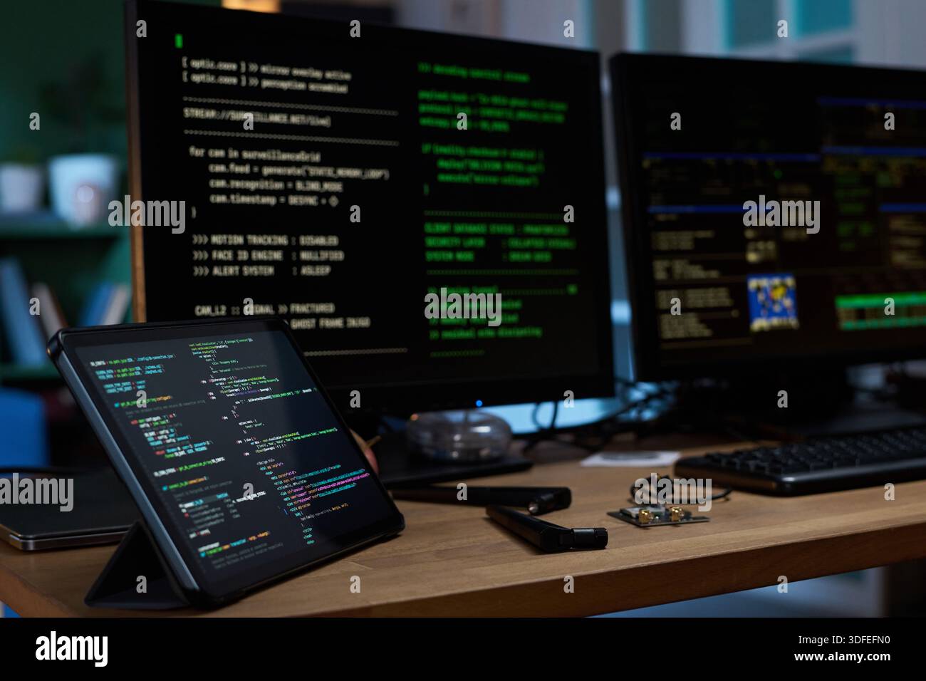 Close up of Tablet and Monitors Displaying Programming Code in Office Stock Photo