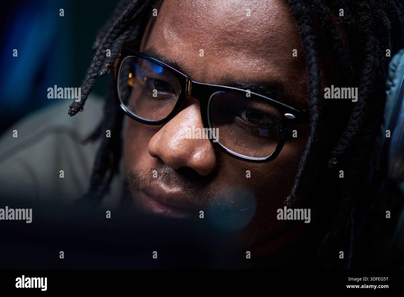 Young Black Man Wearing Glasses Concentrating While Using Computer Stock Photo