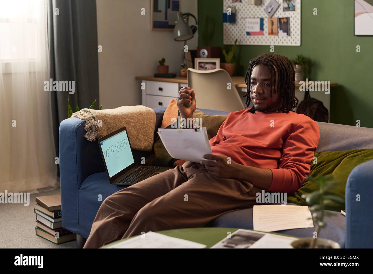 Young Black Man Reviewing Documents While Working Remotely from Home Stock Photo