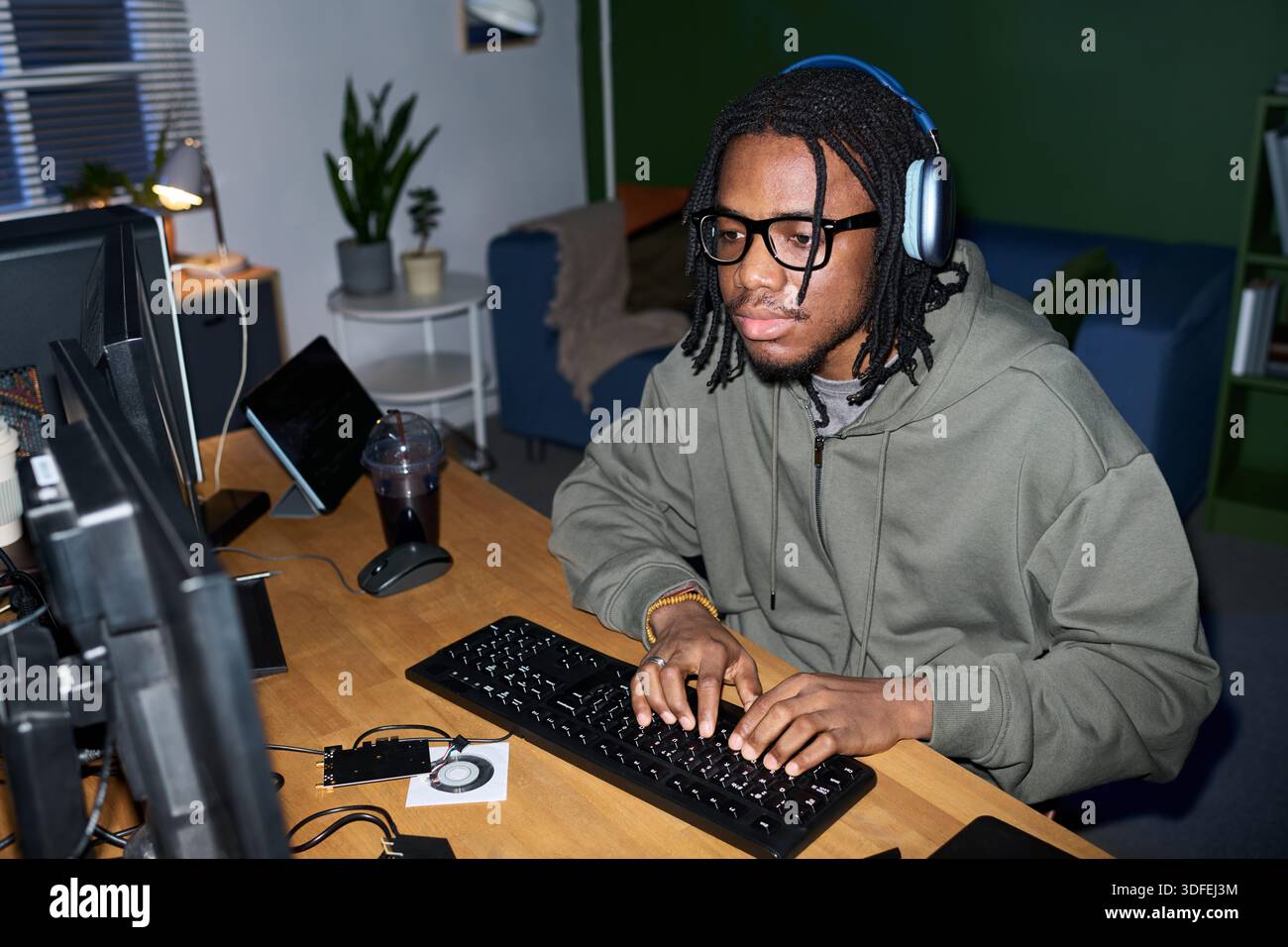 Young Black Man Wearing Headphones Using Computer While Working Stock Photo