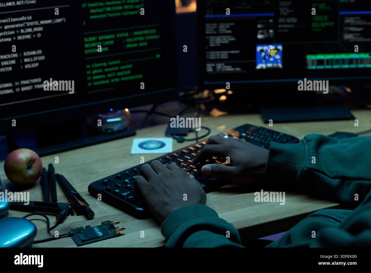 Young Black Man Typing Code on Computer Keyboard in Dark Office Stock Photo