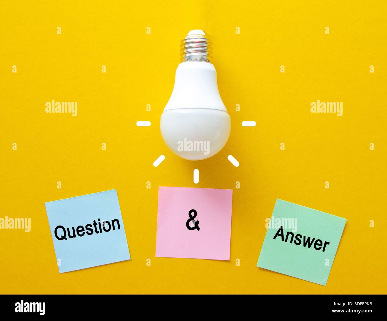 Light bulb shining above pink sticky notes with question marks and text Stock Photo