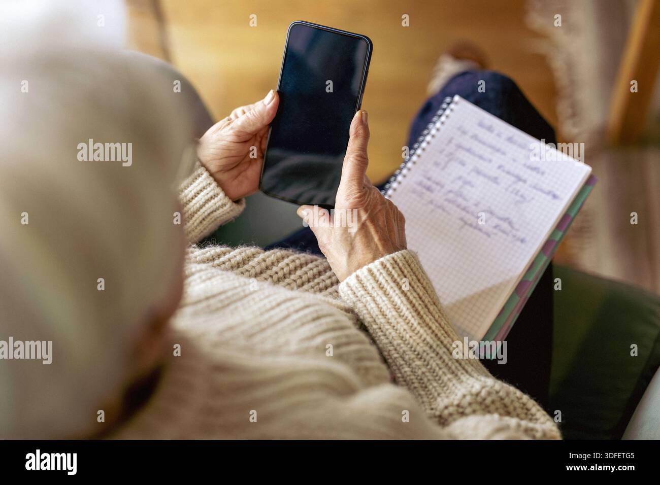 Senior woman using written notes and mobile phone Stock Photo