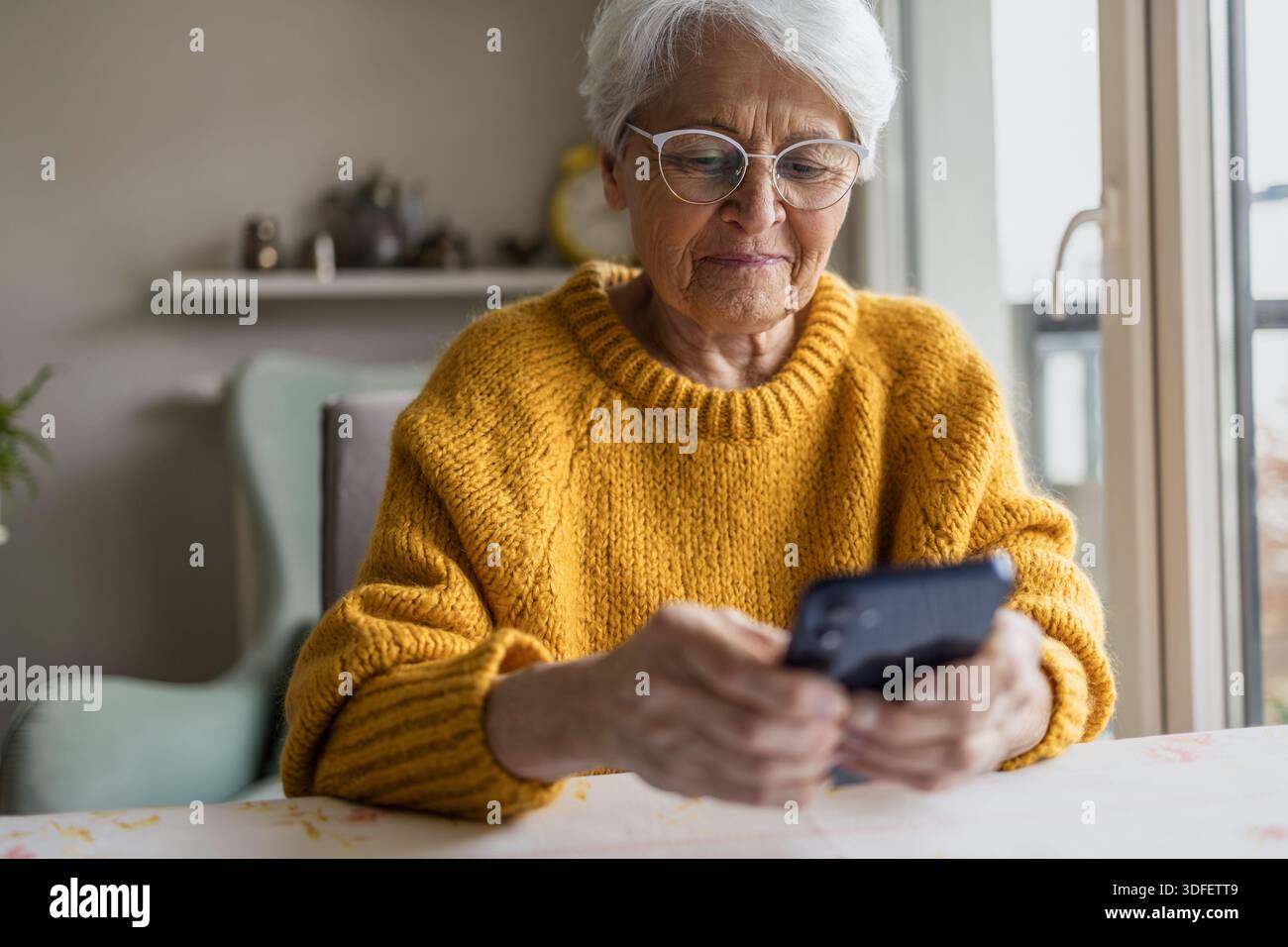 Senior woman using smart phone at home Stock Photo
