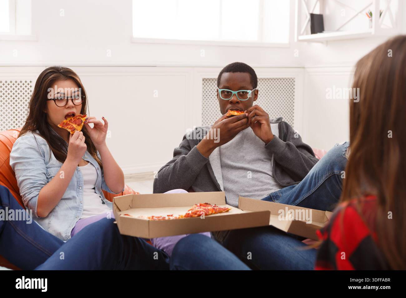 Students sharing pizza at home party Stock Photo
