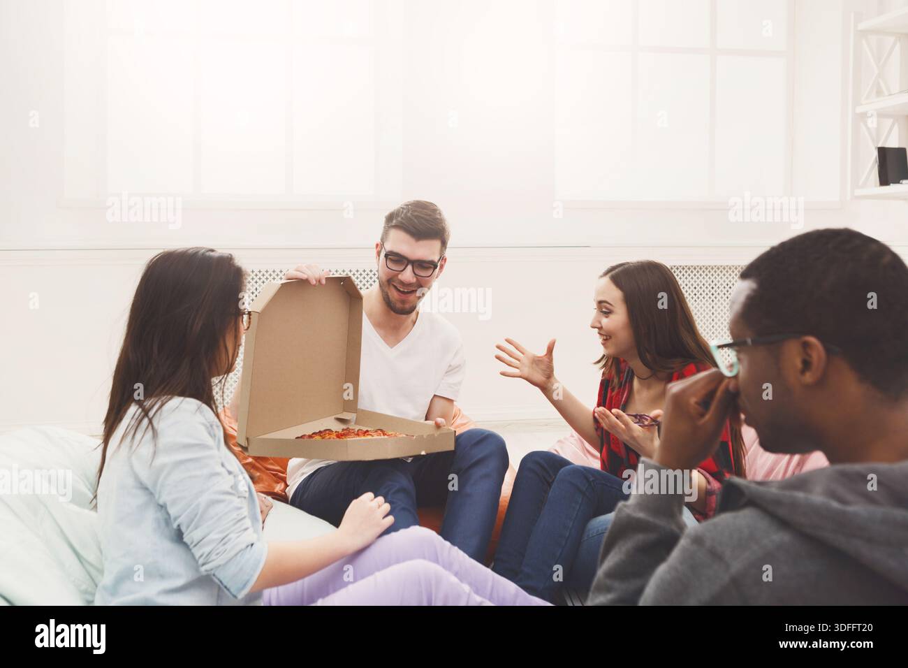 Students sharing pizza at home party Stock Photo