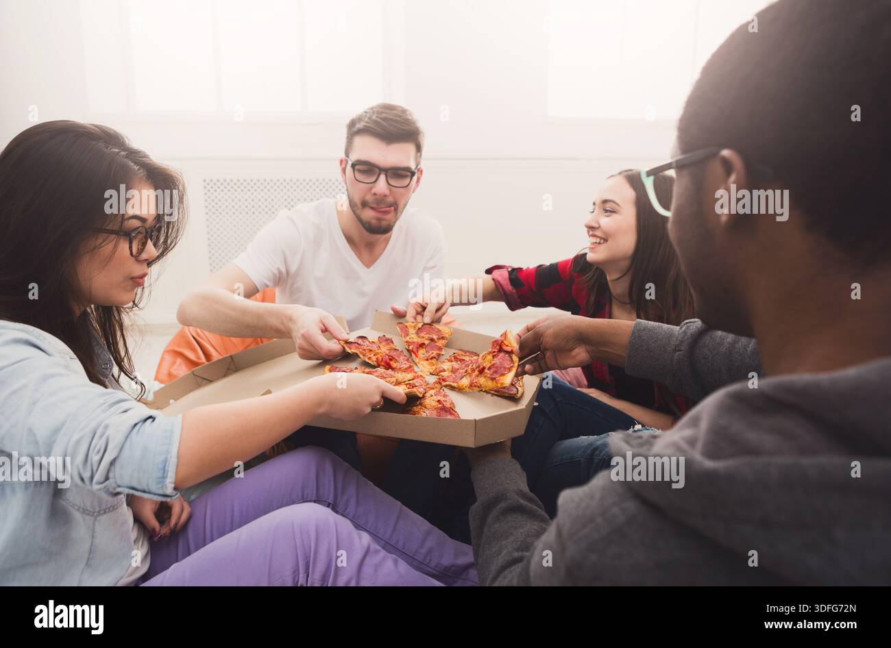 Students sharing pizza at home party Stock Photo