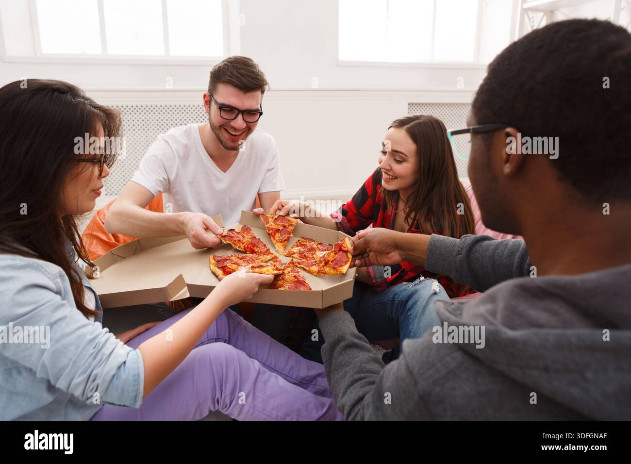 Students sharing pizza at home party Stock Photo