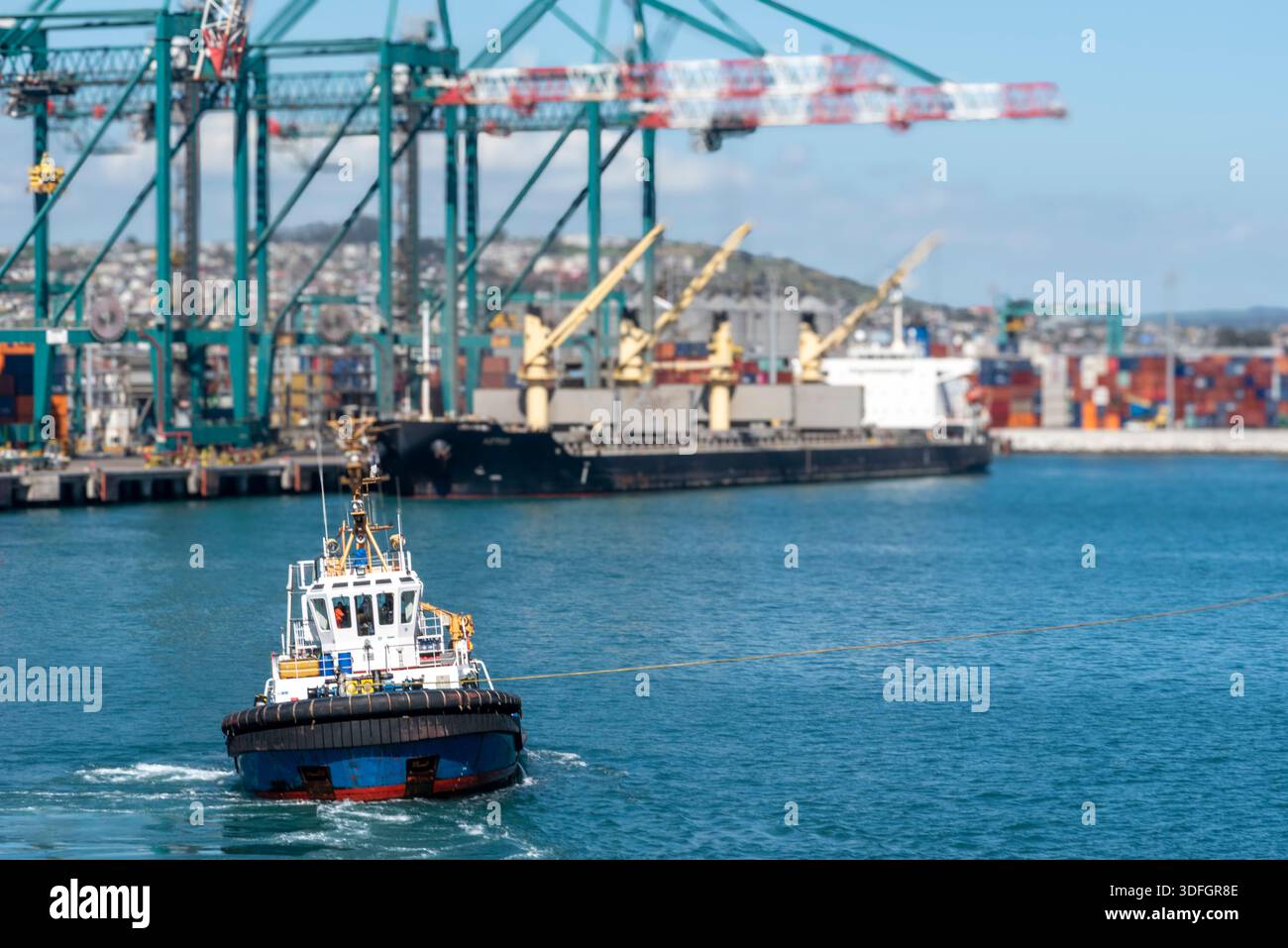 Harbor tug assisting commercial vessel during port maneuvering ...