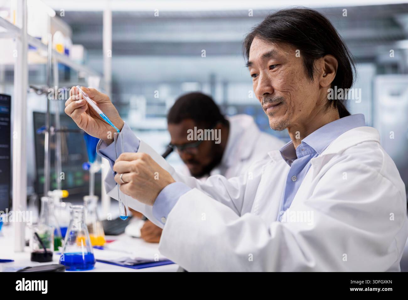 Close up of biochemist using pipette to transfer chemical sample into ...