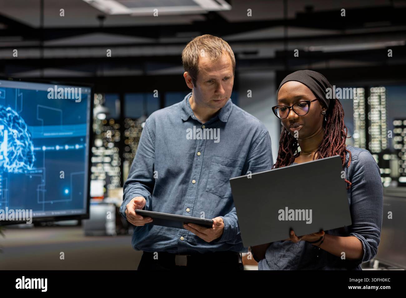 Manager and intern in office automating repetitive tasks using AI scripts on devices. Team leader and trainee work together using artificial intelligence to speed up feature implementation Stock Photo