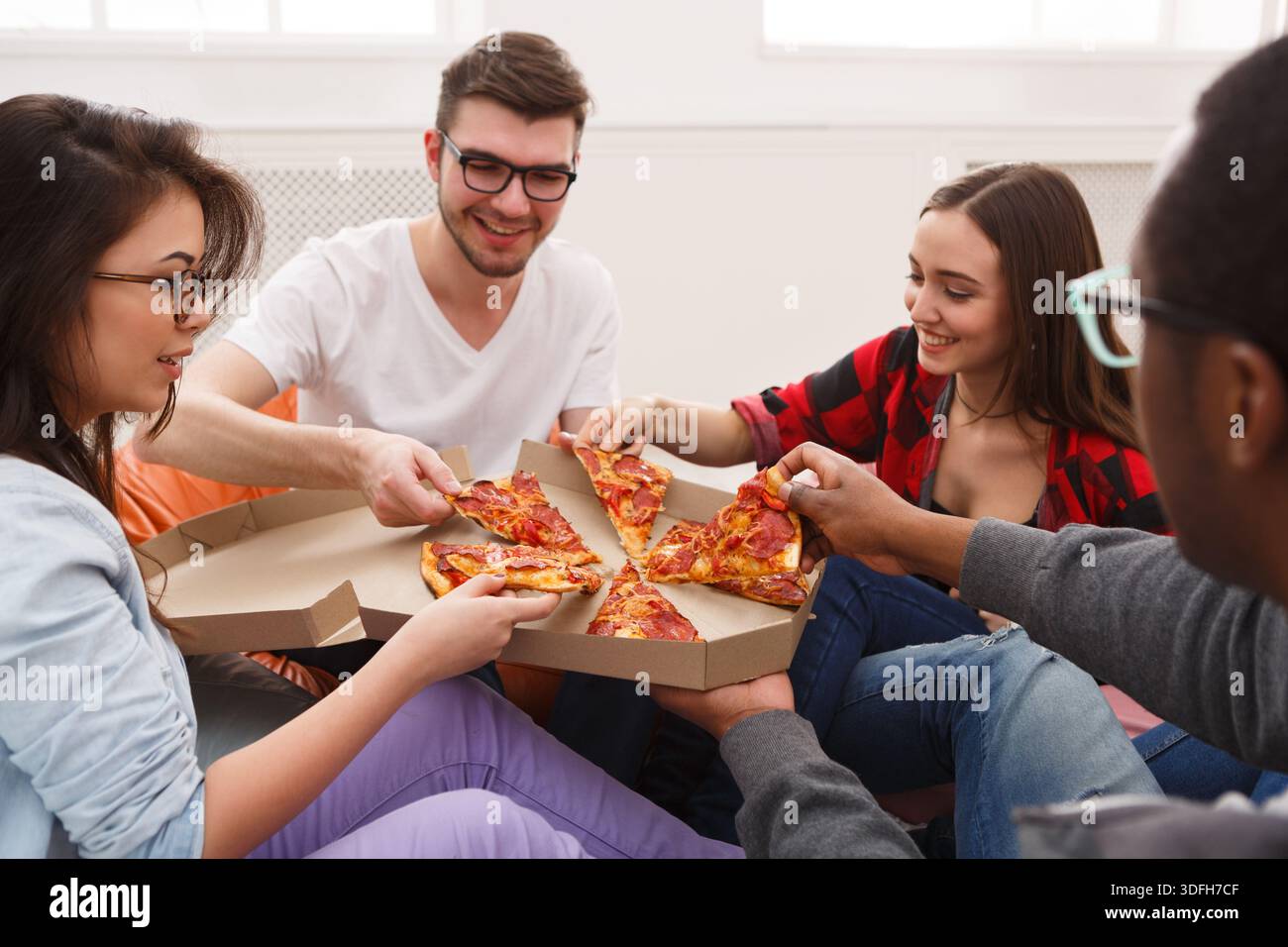 Students sharing pizza at home party Stock Photo
