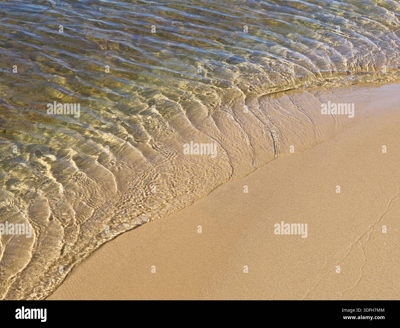 Wavelets form in receding lake waters on smooth sandy beach Stock Photo