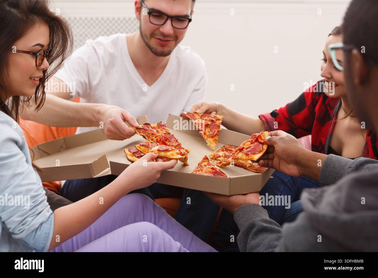 Students sharing pizza at home party Stock Photo