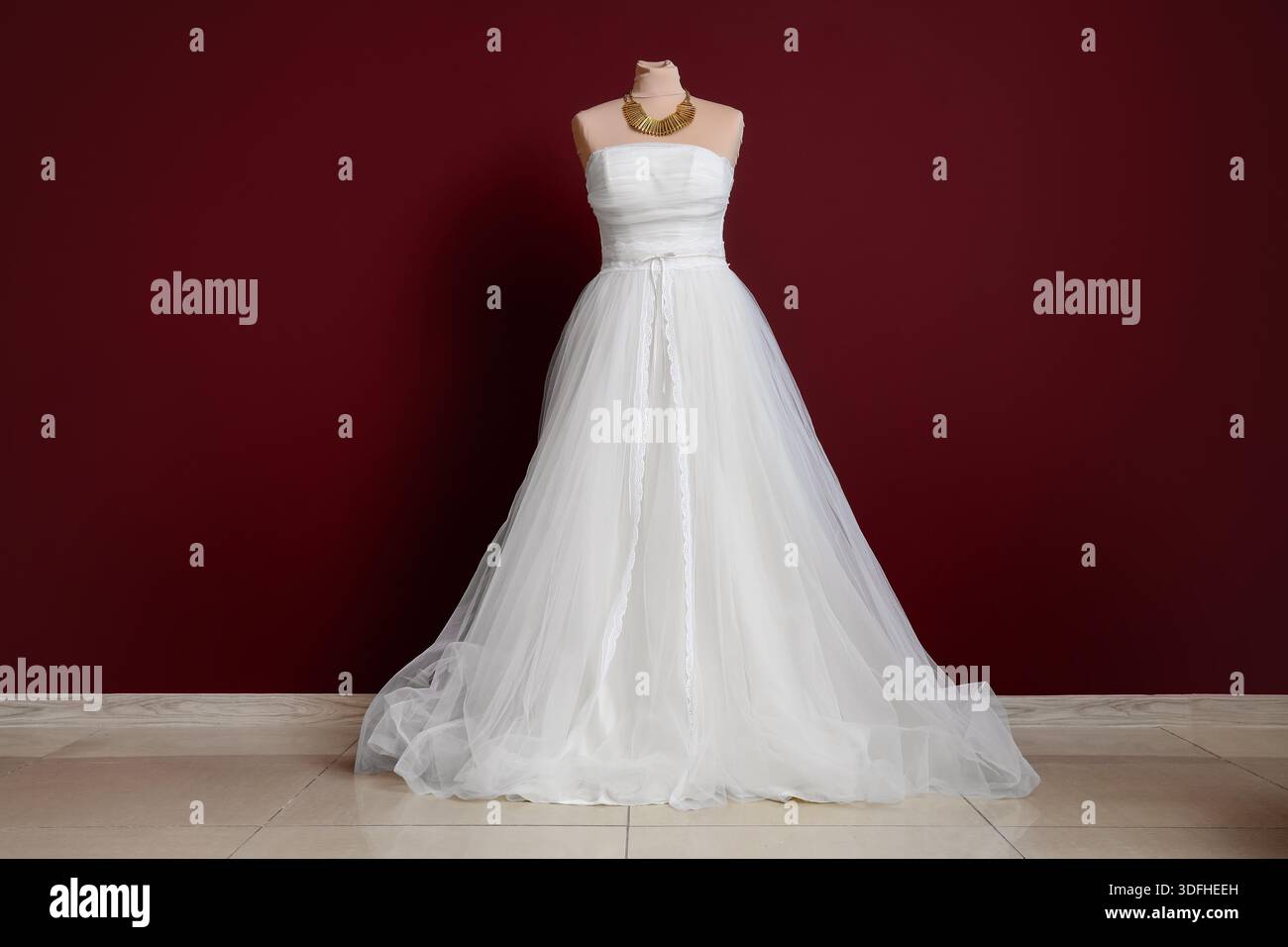 Mannequin with white wedding dress near burgundy wall Stock Photo - Alamy