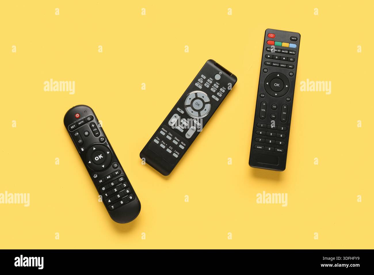 Different modern TV remote controls on yellow background Stock Photo