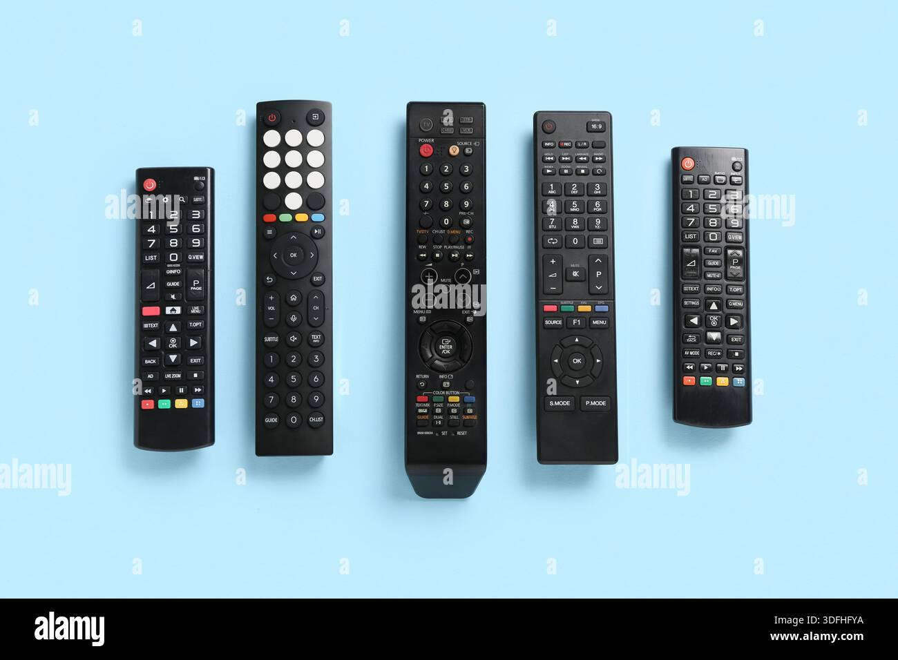 Different modern TV remote controls on blue background Stock Photo