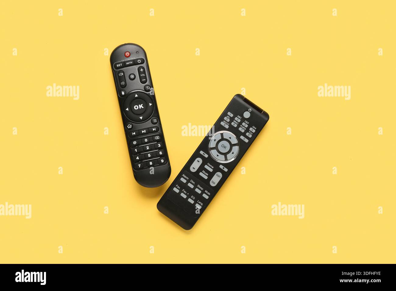 Different modern TV remote controls on yellow background Stock Photo