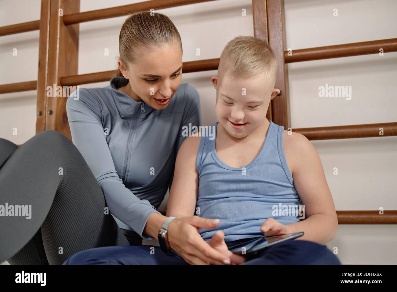Woman Supporting Child with Down Syndrome Using Digital Tablet Stock Photo