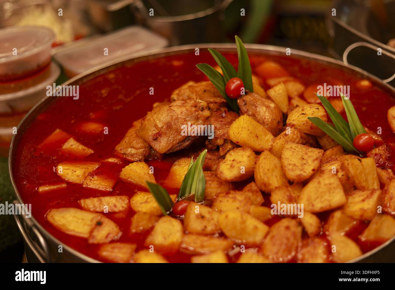 Spicy massaman curry with chicken and potato in big pot featuring delicious authentic thai food with rich red soup ready for serving at local street m Stock Photo