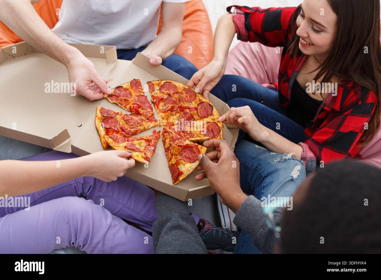 Students sharing pizza at home party Stock Photo