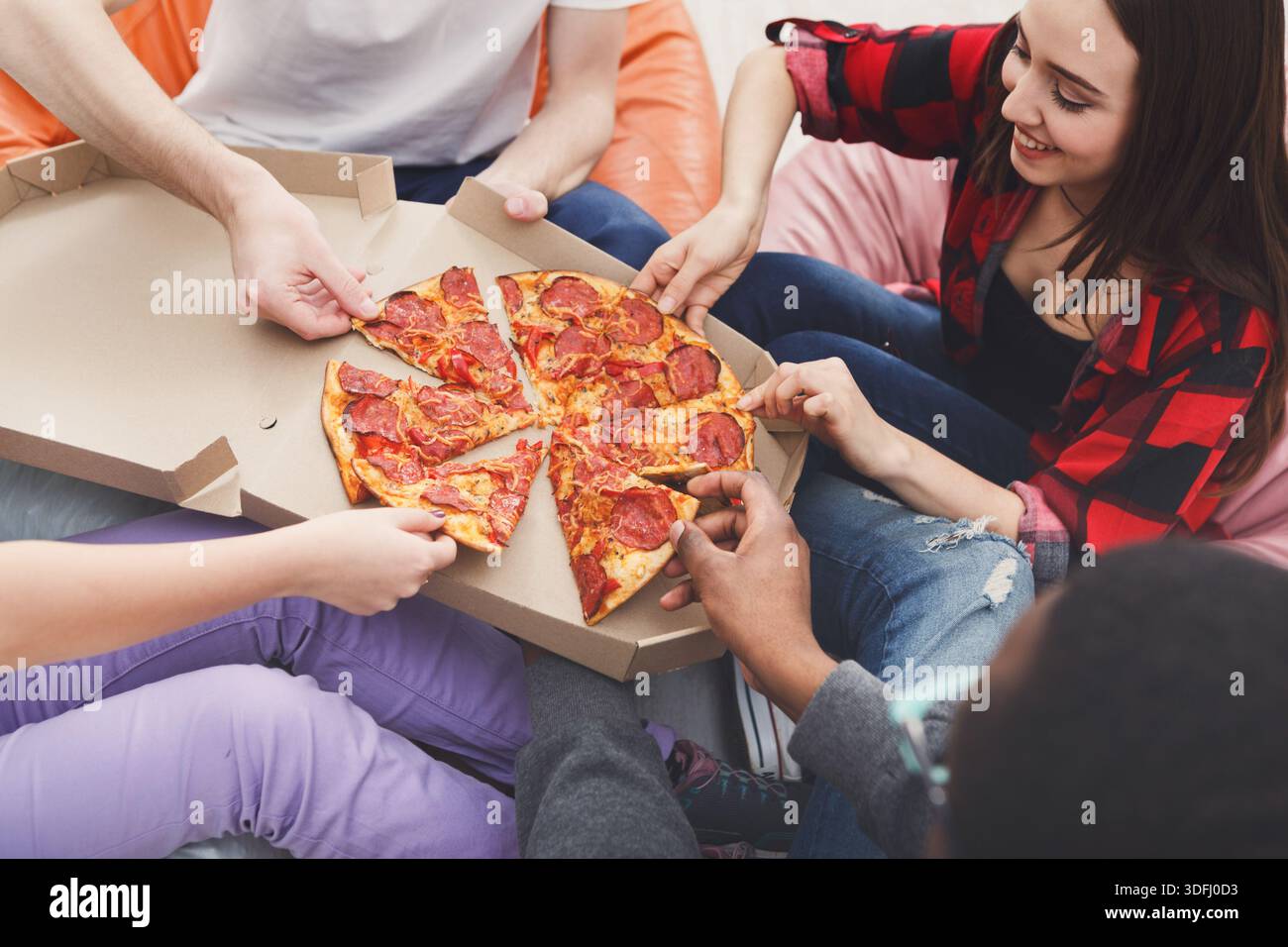 Students sharing pizza at home party Stock Photo