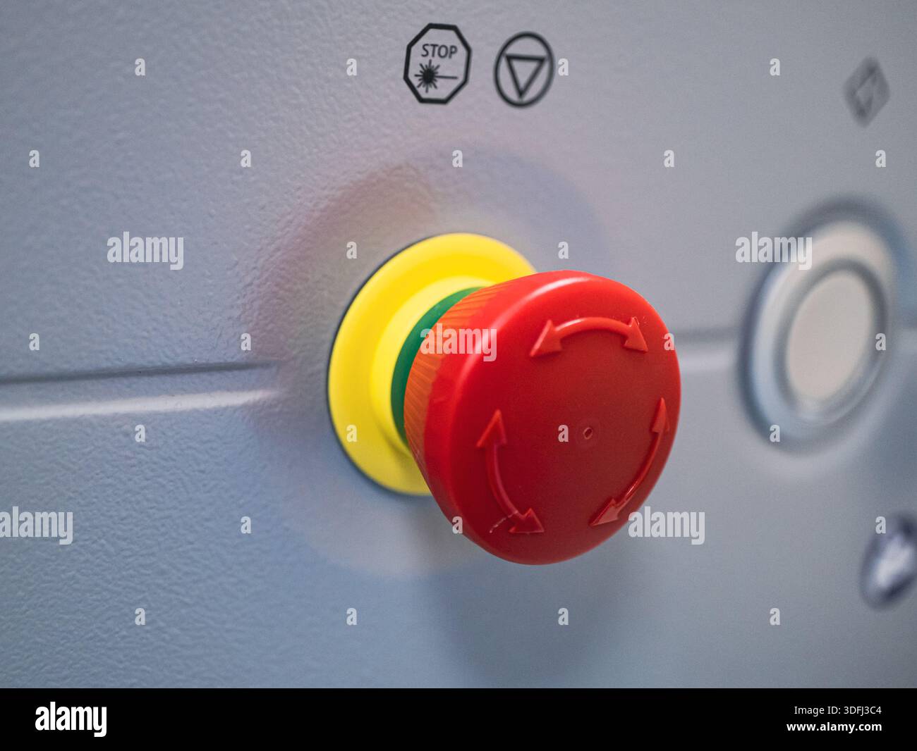 A close-up of a red and yellow emergency stop button on a machine panel ...
