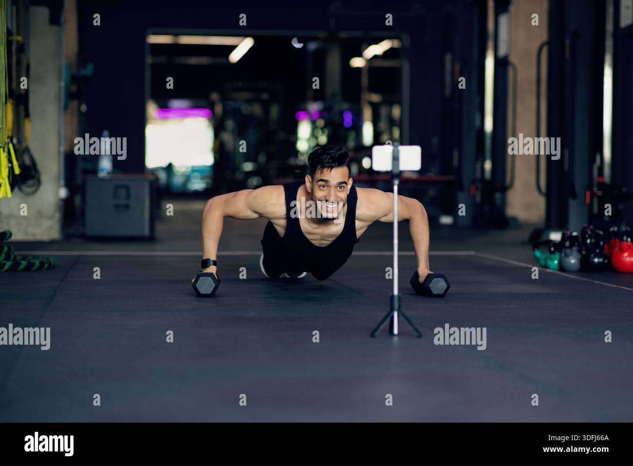 Athletic Arab Man Making Dumbbell Push-Ups While Recording Content On Smartphone Camera Stock Photo