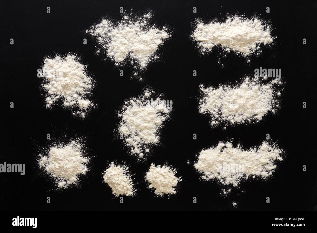 Sprinkled wheat flour splash spots on black background Stock Photo