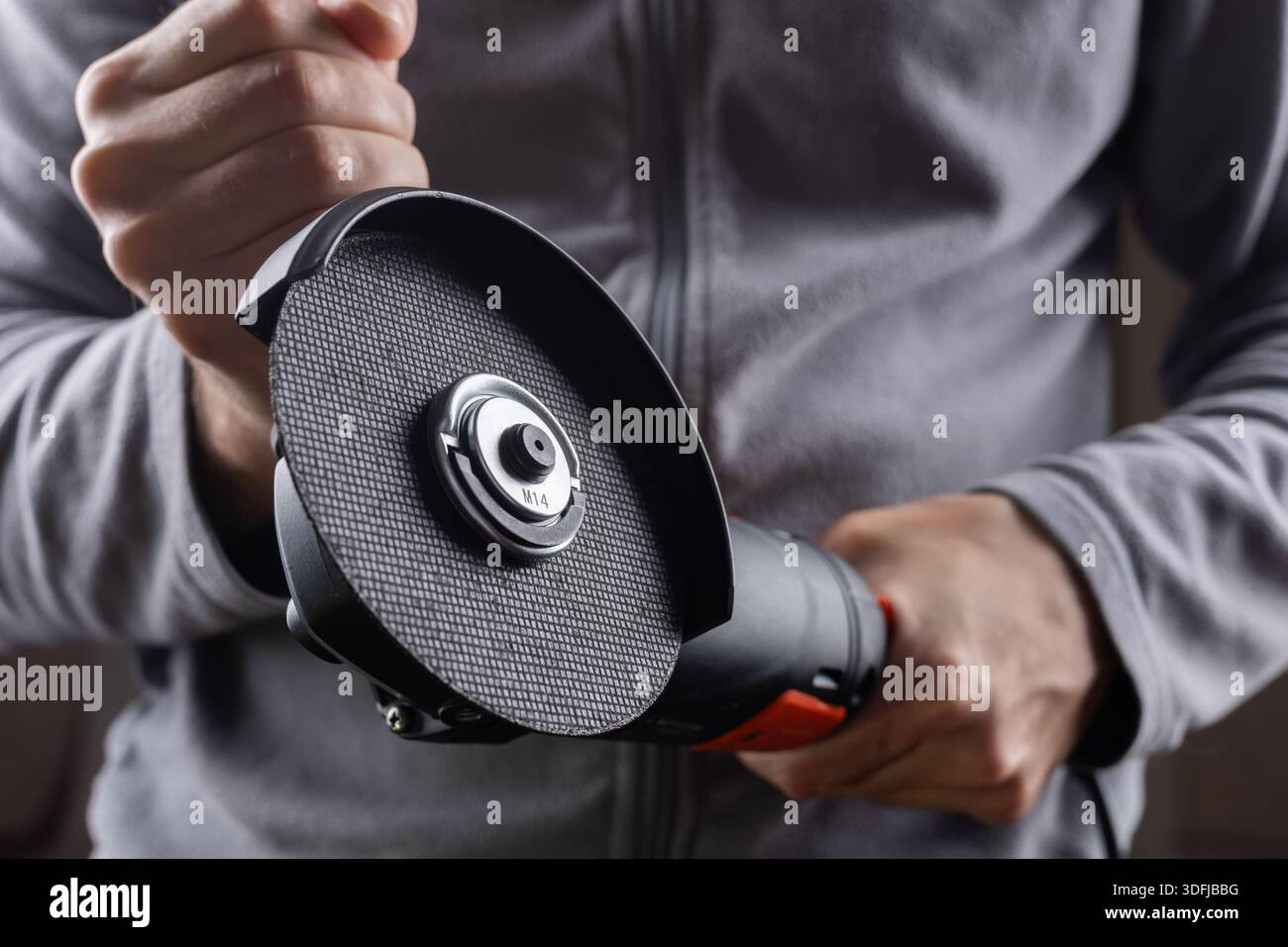 worker hold grinder tool on dark background. Stock Photo