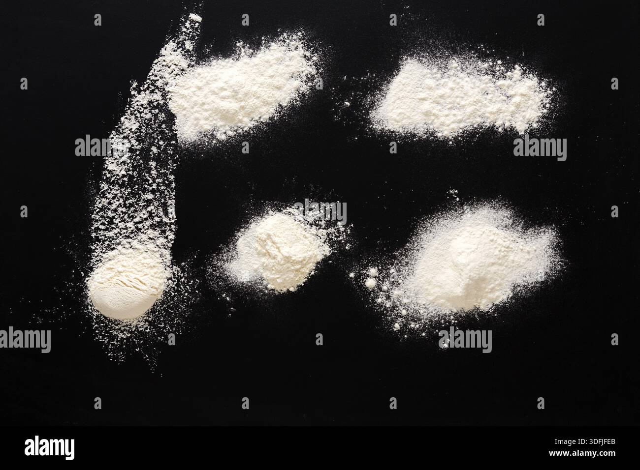 Sprinkled wheat flour splash spots on black background Stock Photo