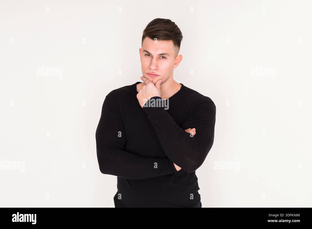 Thoughtful Young Man Posing With Arms Crossed in a Minimalist Setting Stock Photo