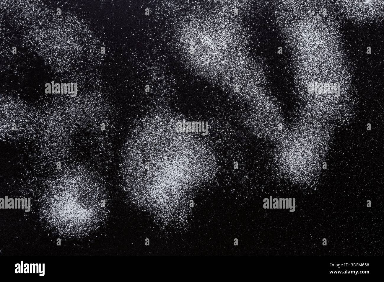 Sprinkled wheat flour splash spots on black background Stock Photo