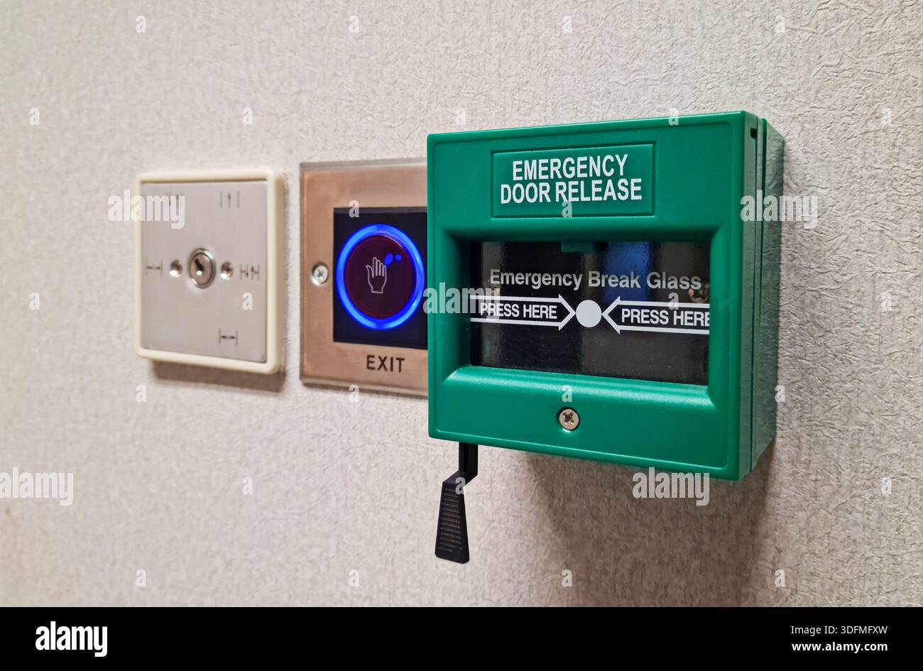 Multiple building access control devices mounted on a textured interior wall. Components include a key switch for security override, a sensor-based to Stock Photo