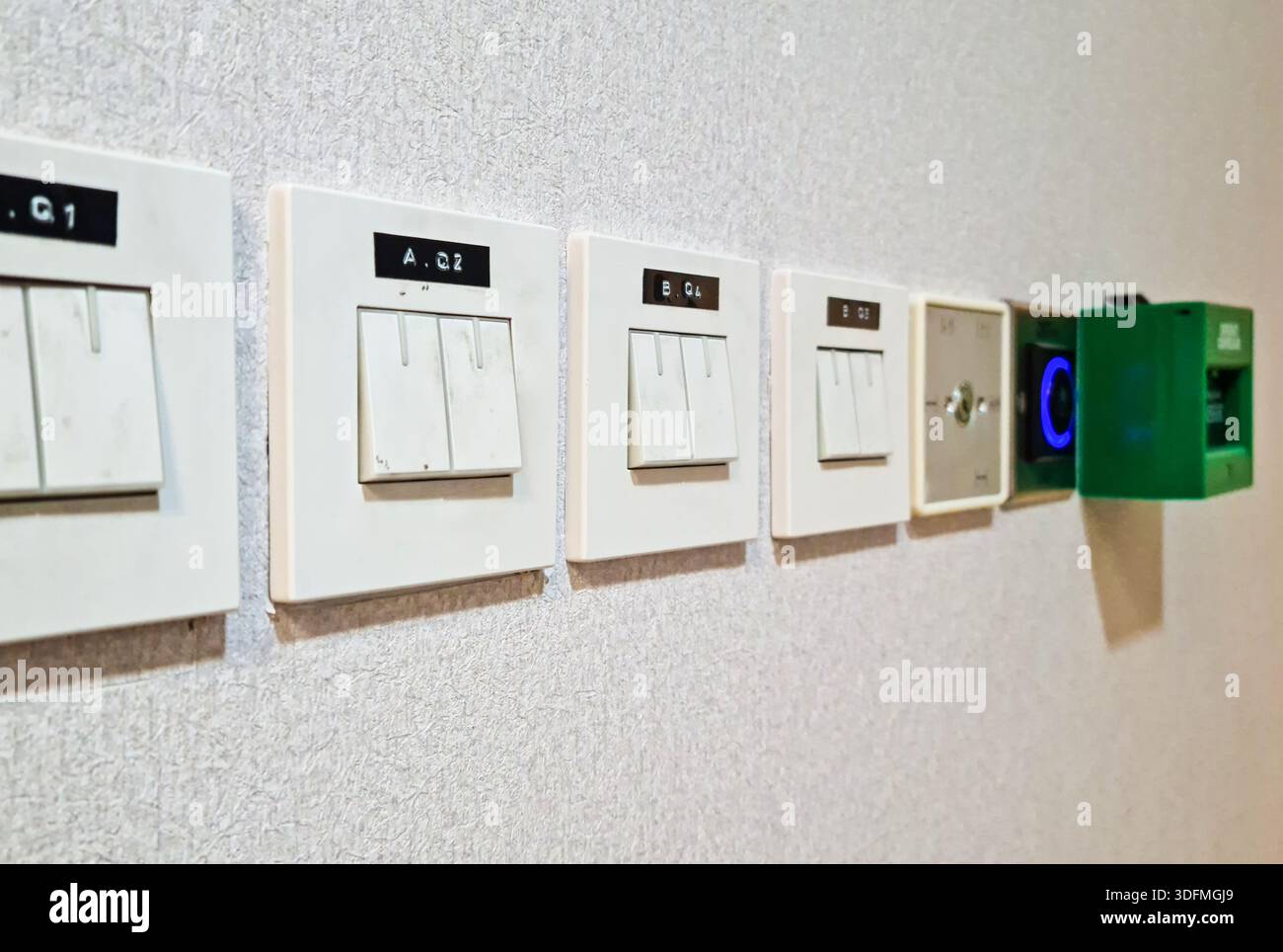 Multiple building access control devices mounted on a textured interior wall. Components include a key switch for security override, a sensor-based to Stock Photo
