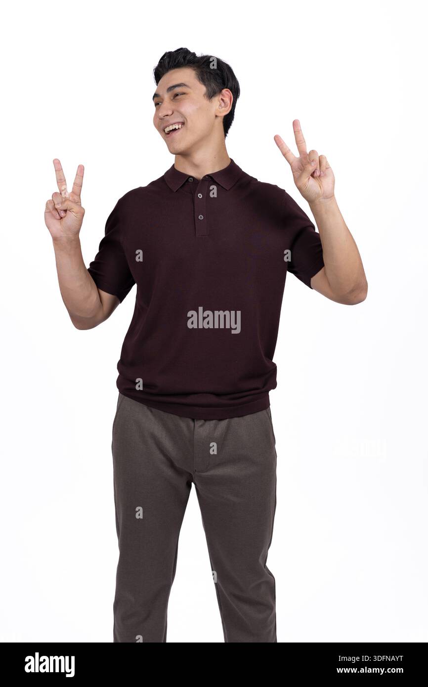 Young Man Gesturing Peace Symbol and Smiling on White Background Stock Photo